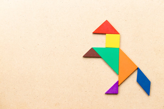 Color tangram puzzle in horse or mustang shape on wood background