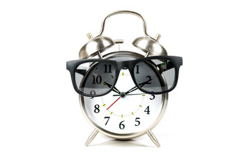 Old fashioned alarm clock wearing sunglasses over white