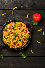 Pasta skillet dish top view. This quick & delicious pasta meal is made with penne pasta, fresh tomato sauce and sausage. This italian inspired comfort food is cooked and served in a cast iron skillet.