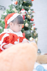 Obraz na płótnie Canvas Merry christmas happy little child in santa red hat with beautifully decorated christmas tree holidays in home, christmas concept
