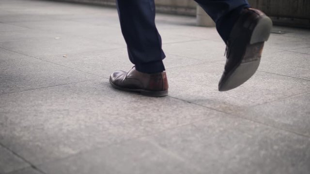 Close-up of the shoes of a walking businessman on the street