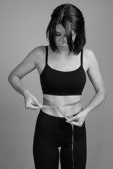 Young beautiful woman ready for gym against gray background