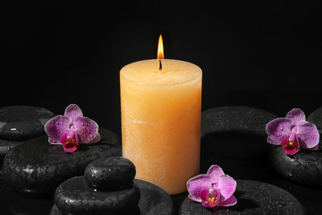 Fototapeta na wymiar Composition with candle and spa stones on black background