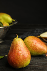 Ripe juicy pears on dark wooden table against black background. Space for text