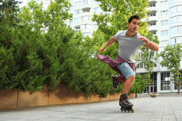 Handsome young man roller skating outdoors. Recreational activity