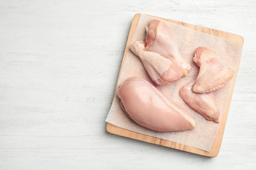 Cutting board with fresh chicken meat on white wooden table, flat lay. Space for text