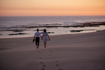 Couple walking towards beach during sunset