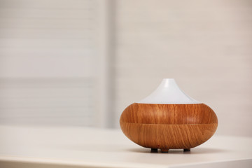 Modern essential oil diffuser on table indoors. Space for text