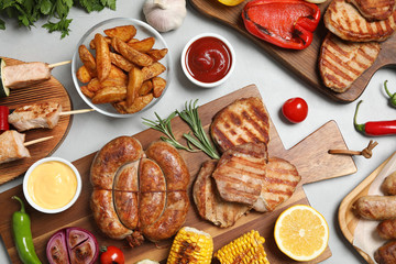 Flat lay composition with barbecued meat and vegetables on light table