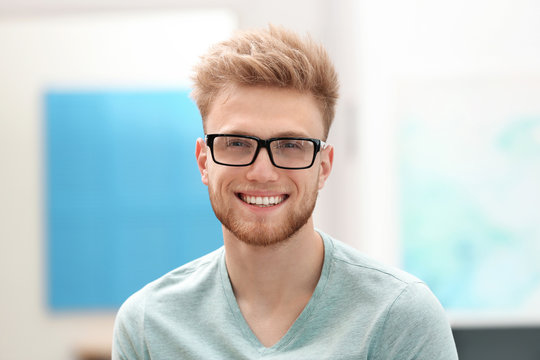 Portrait of handsome young man with glasses in room