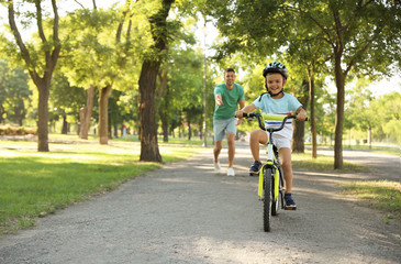 Happy father teaching his son to ride bicycle in park