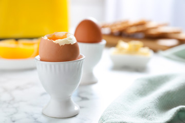 Cups with soft boiled eggs on marble table, space for text. Healthy breakfast