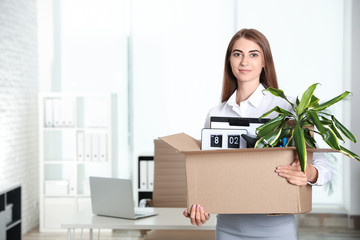Happy young woman holding box with stuff at office