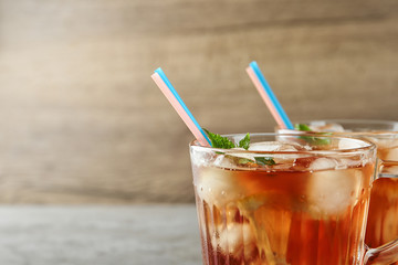 Cups of refreshing iced tea against wooden background, closeup. Space for text