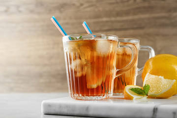 Cups of refreshing iced tea on table against wooden background