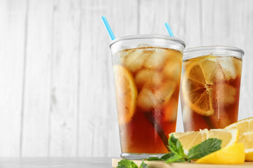 Glasses of refreshing iced tea against white wooden background. Space for text