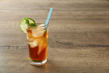 Glass of refreshing iced tea on wooden table. Space for text