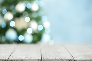 Empty white wooden table and blurred fir tree with Christmas lights on background, bokeh effect....