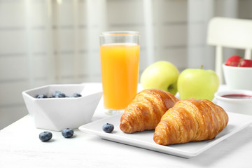 Tasty breakfast with croissants served on white wooden table