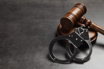 Judge's gavel and handcuffs on grey background, space for text. Criminal law concept