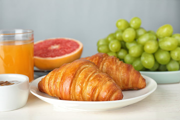Delicious breakfast with croissants served on white wooden table