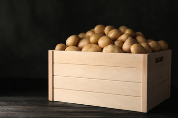 Raw fresh organic potatoes on wooden table against dark background