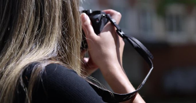 Female photographer taking street photos - close up from behind over shoulder