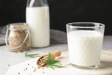 Composition with glass of hemp milk on light table against black background. Space for text