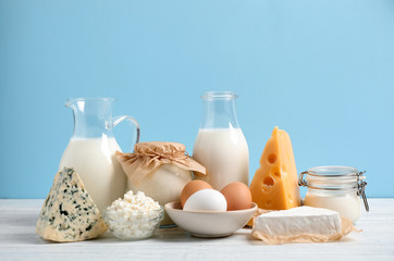 Different dairy products on white table against blue background