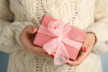 Young woman holding Christmas gift, closeup view
