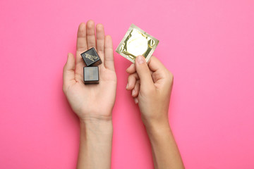Woman with sex dice and condom on pink background, top view