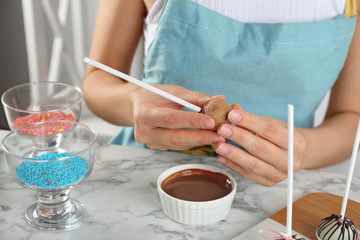 Fototapeta na wymiar Young woman with cake pop and chocolate frosting at white marble table, closeup