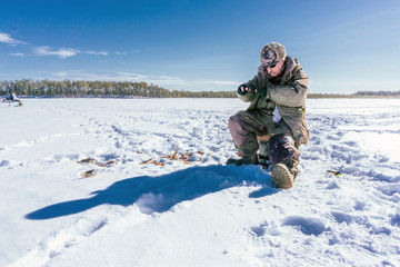 Fototapeta na wymiar winter fishing Fisherman enjoying a day on the ice