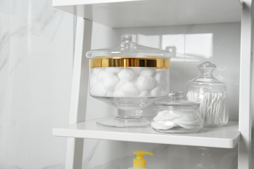 Fototapeta na wymiar Cotton balls, swabs and pads on white shelf in bathroom