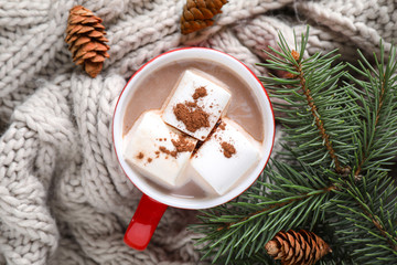 Cup of tasty cocoa with marshmallows on knitted cloth, flat lay