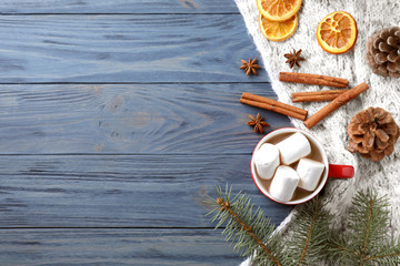 Flat lay composition of tasty cocoa with marshmallows on blue wooden table. Space for text