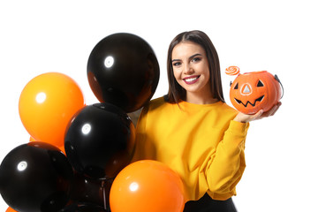 Fototapeta na wymiar Beautiful woman with balloons and Jack O'Lantern candy container on white background. Halloween party