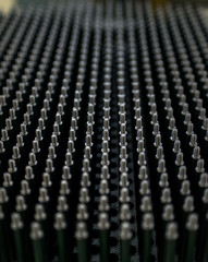 Close up shot of black screw thread bolts rowed up to a pattern background Art