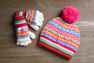 Fototapeta na wymiar Warm knitted hat and mittens on wooden background, flat lay