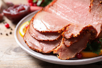 Delicious ham served with garnish on wooden table, closeup