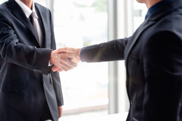 Close up two businessmen partners are standing shaking hands after the business mission deal is completed successfully.