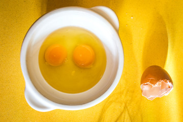 Egg yolks with a whisk on a yellow background