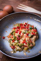 Sauteed vegetables and egg in a pan on wood.