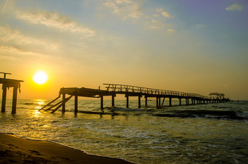 Fototapeta na wymiar Sunset broken bridge on beach with sky