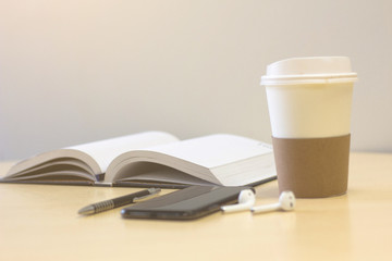 Smartphone  with Book turning pages  and a cup of coffee on wood table