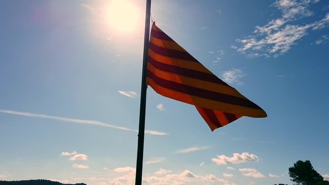 Catalan flag in the sun with a blue sky and some clouds. Catalonia, Spain, Europe.