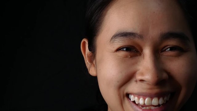 Close up Face of woman crying with smile on black background.