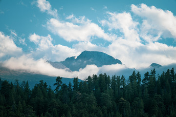 Shot of mountain peak poking through white puffy clouds on a sunny fall afternoon, RMNP Colorado