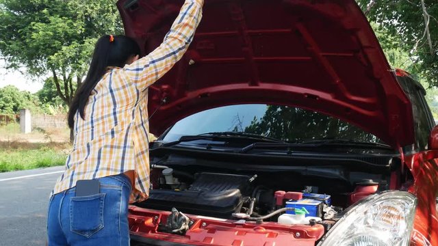 Asian young woman trying to fix this broken car on the street and want to helping.