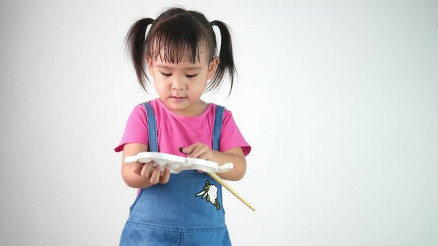 Portrait of adorable little asian girl holding a paintbrush for painting isolated on white background.